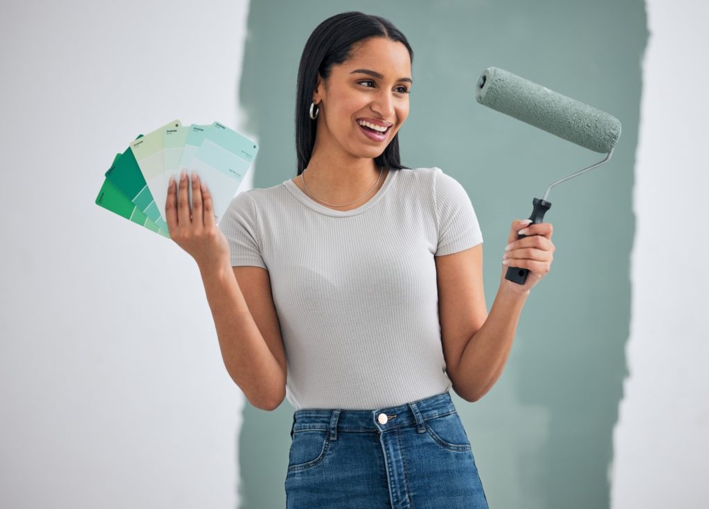 Interior design, green paint and woman doing home renovation with paintbrush roller and color cards